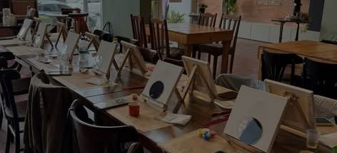 Mesas postas com cavaletes e telas para a experiência com arte